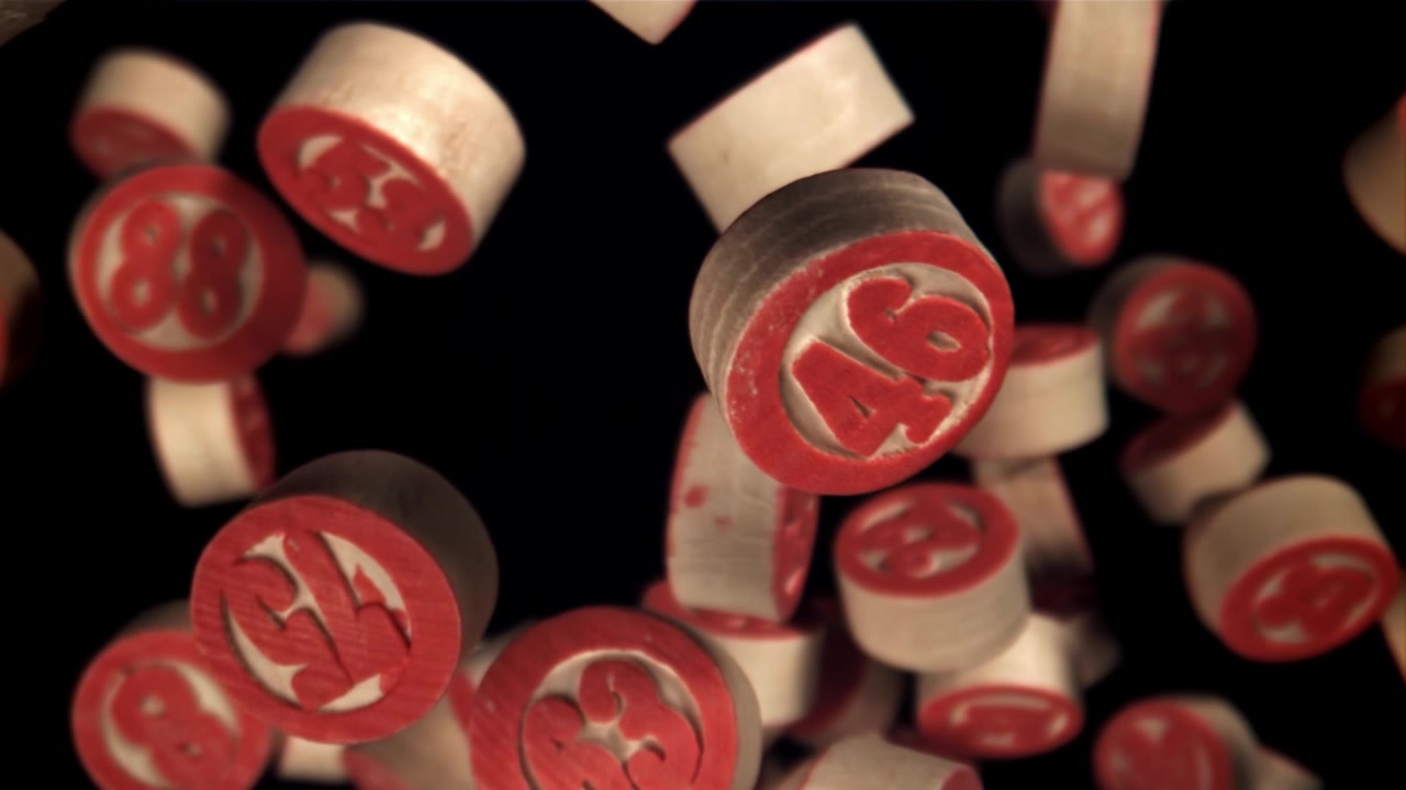 Bolas de bingo de madera cayendo con números rojos sobre un fondo negro