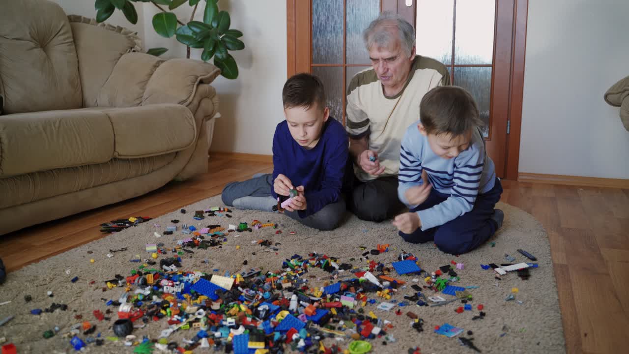 Boys playing lego toys at home. Funny cute children playing lego at home with grandfather