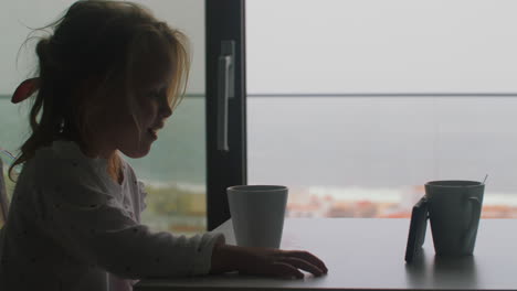 niño viendo dibujos animados en el teléfono en el desayuno