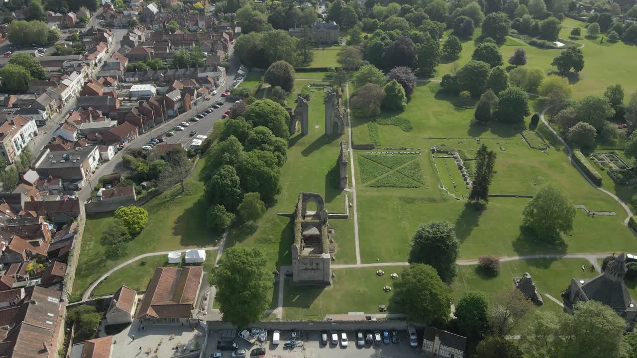 Aerial view of the Glastonbury Abbey ruins an 8th century monastery and gardens. Drone moving forwards in the direction of the ruins and Glastonbury town on the left side. 4K, 60fps.