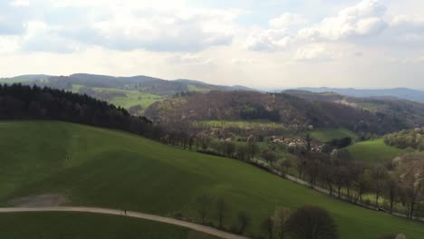 Descending-over-beautiful-German-hill-side-with-traffic-on-road-and-people-walking