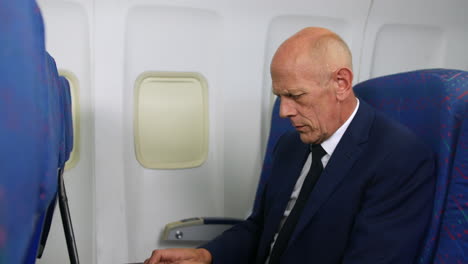 a mature business man working a laptop on an airliner airplane close up