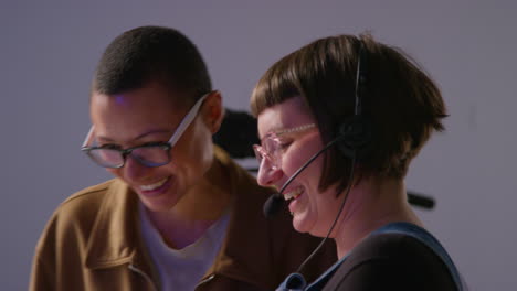 two women laughing while filming in a studio