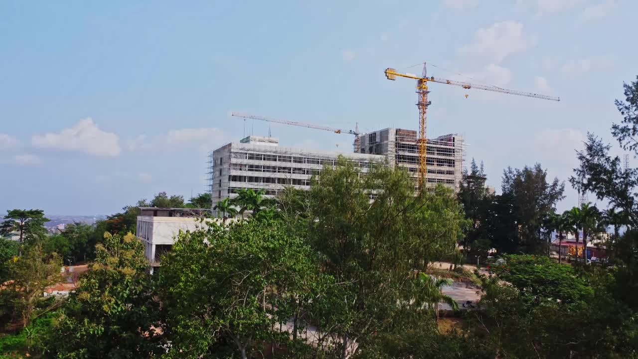 Jib up of a beautiful hotel under construction behind green trees on a sunny day in Ibadan, Nigeria