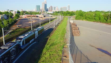 drone tracking light rail train up to charlotte, north carolina skyline