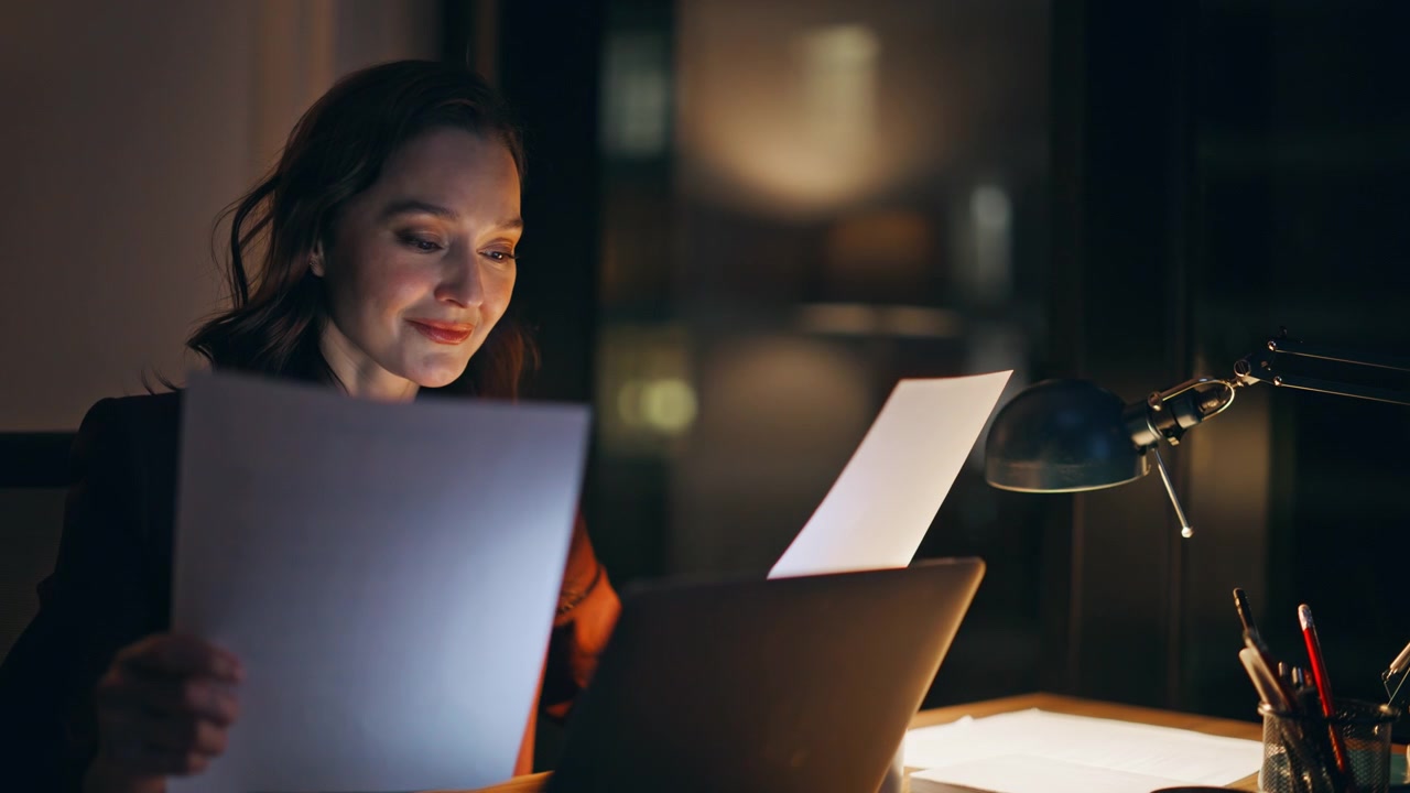 Late businesswoman texting keyboard working in office reviewing papers closeup