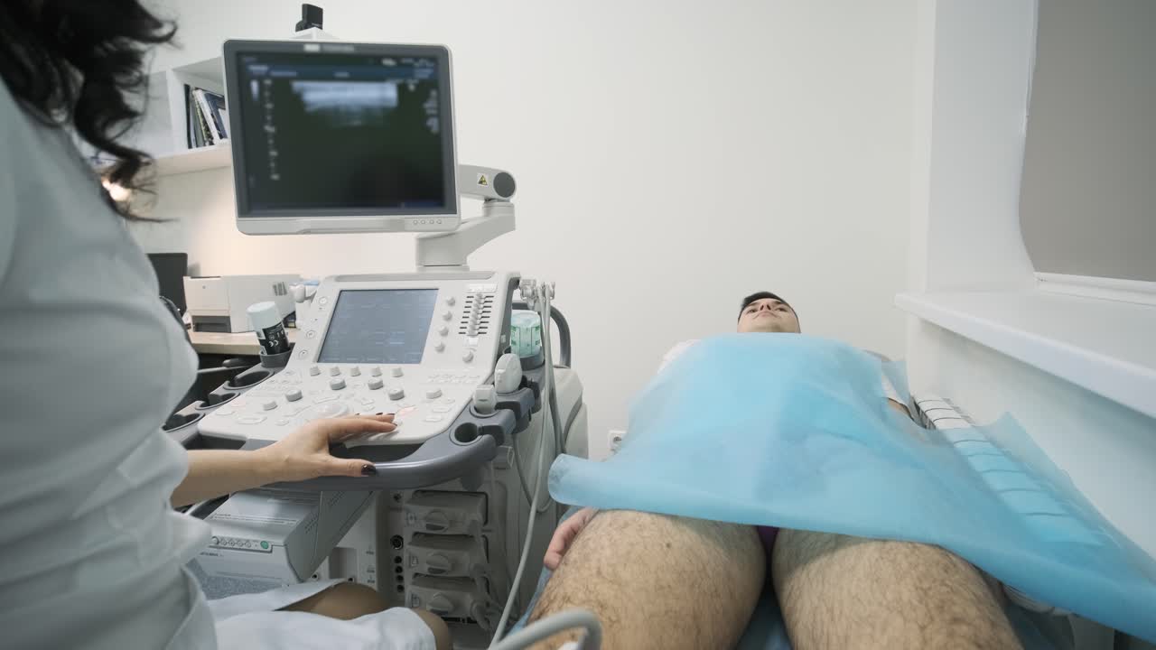 Woman doctor hands examines young man patient knee-joint using ultrasound sensor device, sonography. Doctor runs ultrasound sensor over patient's leg, knee.