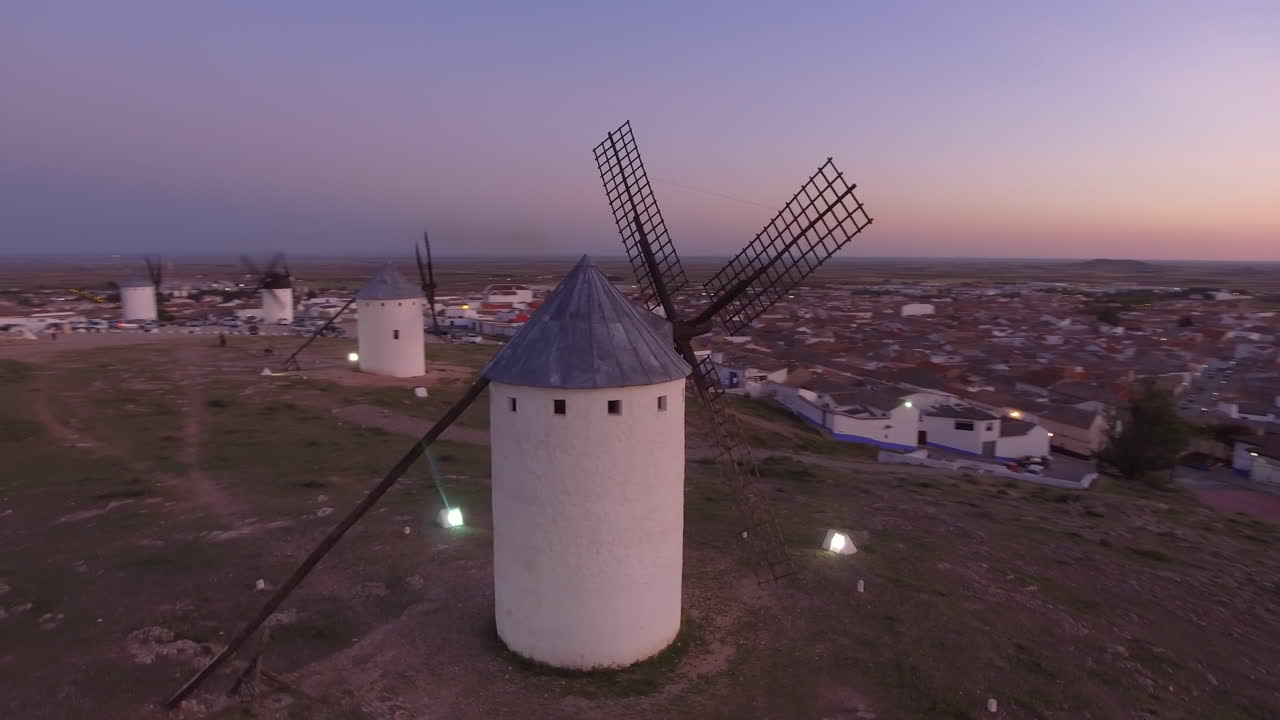 Aerial view Beautiful sunset over white cylindrical towers and pointed roofs of old Spanish windmills on background with Campo de Criptana, Spain
