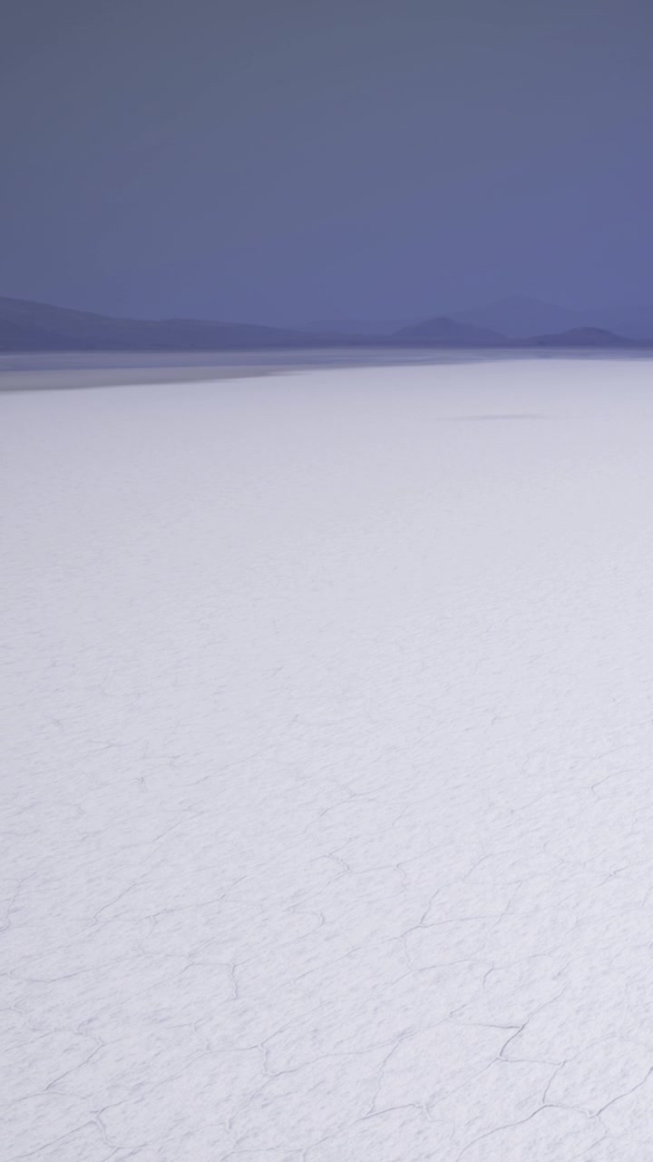 Large salt flat with clear sky and distant mountains during daylight hours