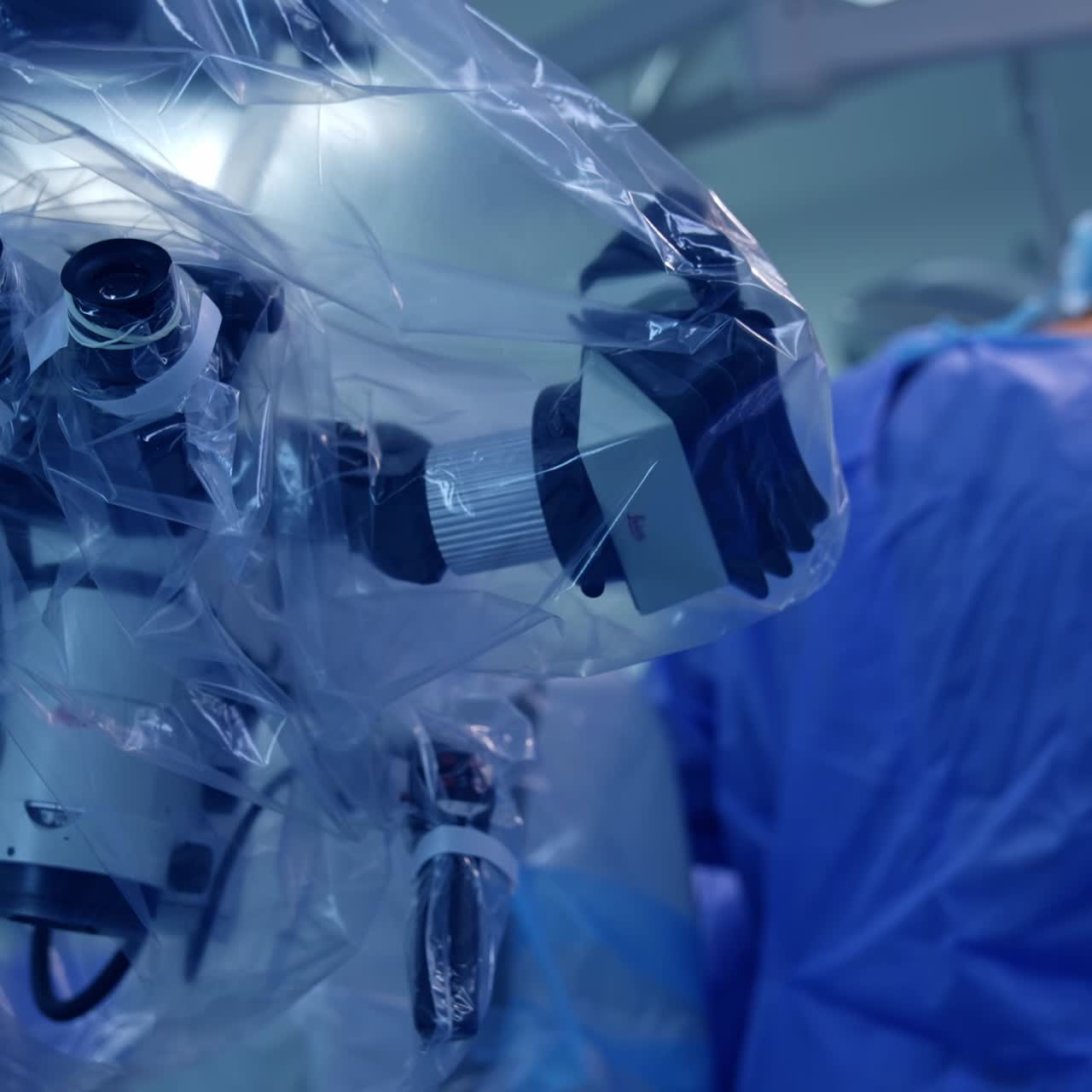 Close look at the technological microscope coated with plastic in surgery room. Surgeons operating patient at backdrop