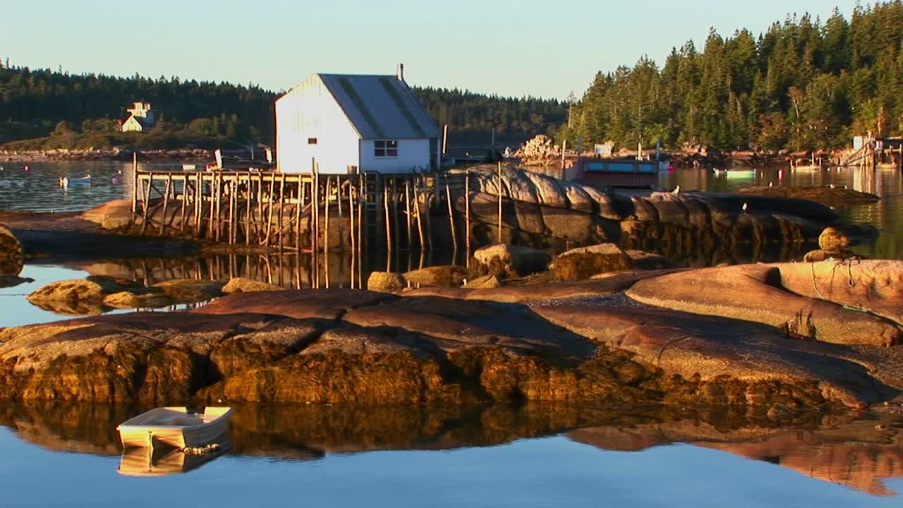 Un piccolo edificio di un villaggio di pescatori di aragoste a Stonington, Maine, si trova su un'isola rocciosa e un molo.