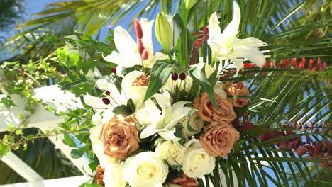 Nice-shot-of-panning-left-to-right-of-flower-arrangement-wedding-venue-decor-and-flowers-outdoor-seating-sandy-beach-engagement-seating-with-tables