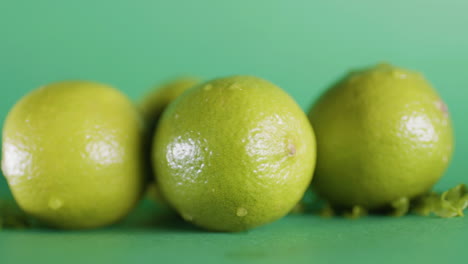 closeup shot of whole fresh lime fruit on isolated green surface