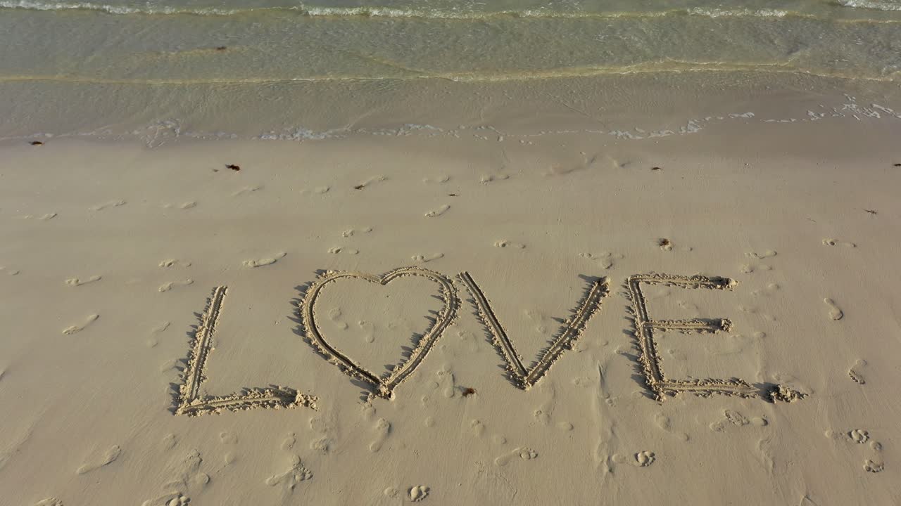 LOVE inscribed in the sand with a parallax effect