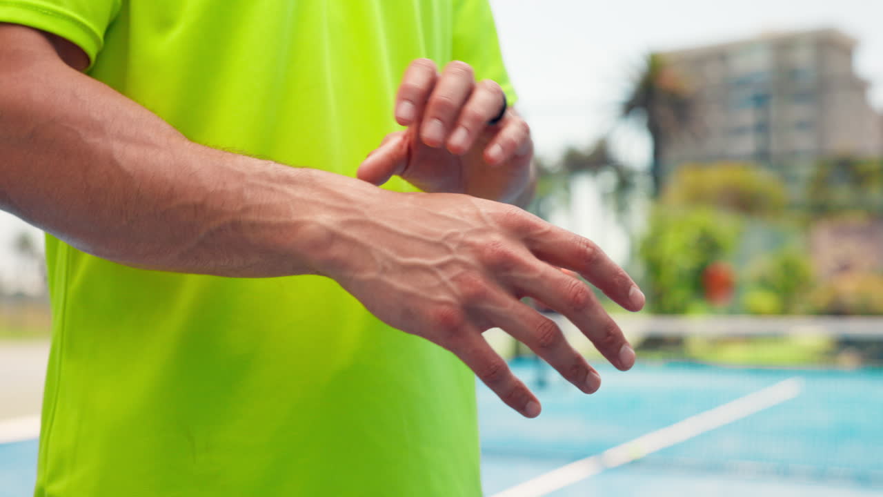 Primo piano di un uomo che si massaggia il polso dolorante su un campo sportivo.