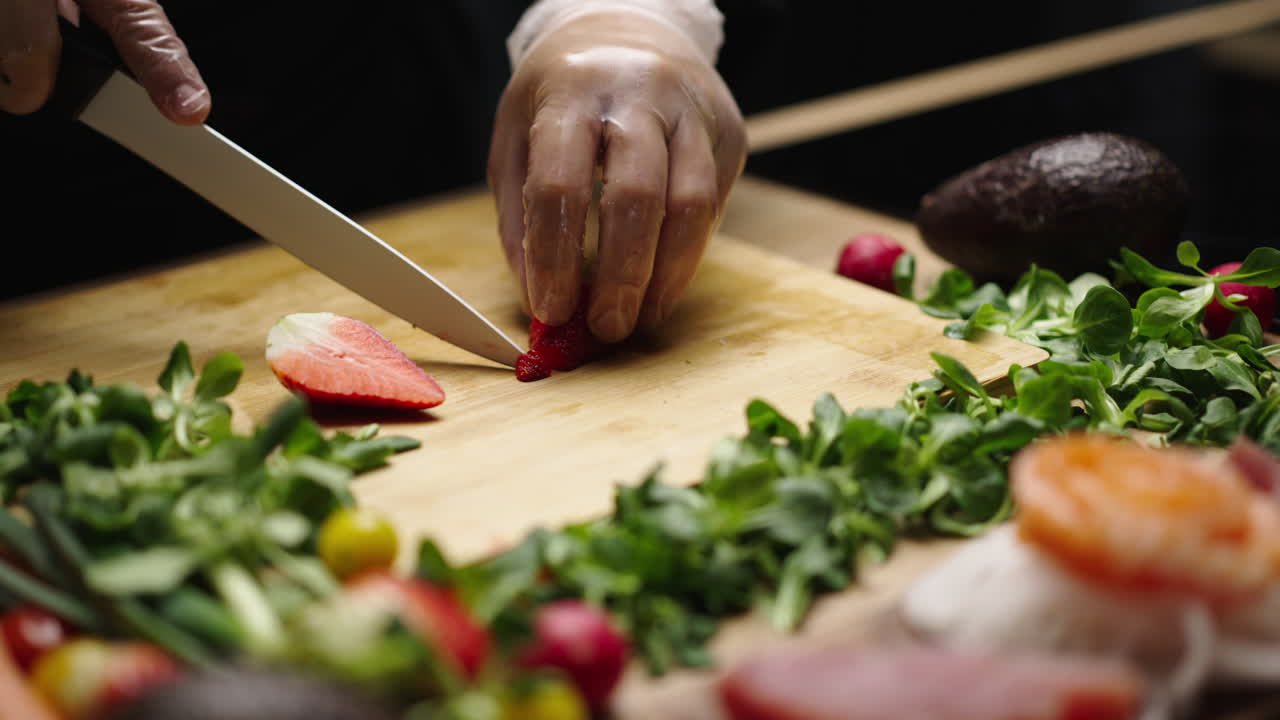 Chef slicing strawberries on a cutting board