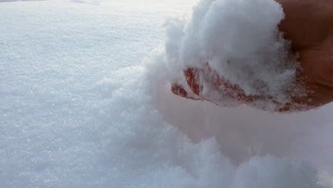 la mano de una persona desnuda está tomando nieve fresca blanca pura en el día de invierno