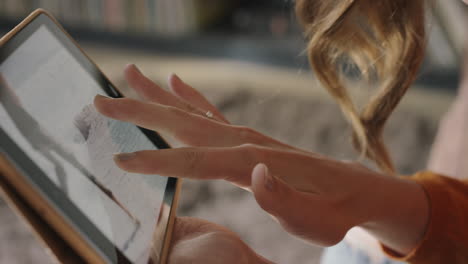 close up of woman using digital tablet at home looking through vacation photographs