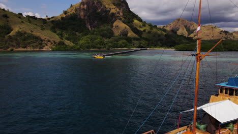 Luftaufnahme-Eines-Holzbootes-An-Der-Blauen-Wasserlandschaft-Des-Flores-Meeres-Mit-Küstenhügeln-Bei-Komodo