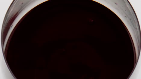 red wine droplet falling glass closeup. smooth liquid surface ripple in circles