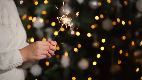 woman holding sparkler near christmas tree