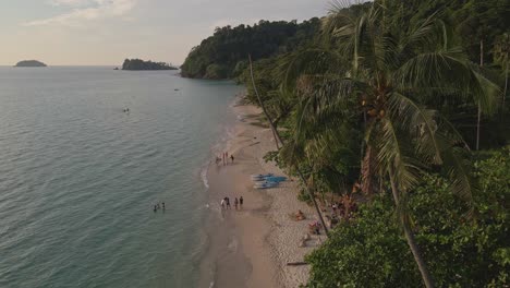 Tropische-Inseldrohne,-Statische-Aufnahme-Aus-Der-Vogelperspektive-Mit-üppig-Grünem-Regenwald-Und-Tropischen-Palmen-Mit-Weißem-Sandstrand-Und-Kleinen-Strandbars-Und-Restaurants-Und-Bungalows-Mit-Einheimischen-Touristen