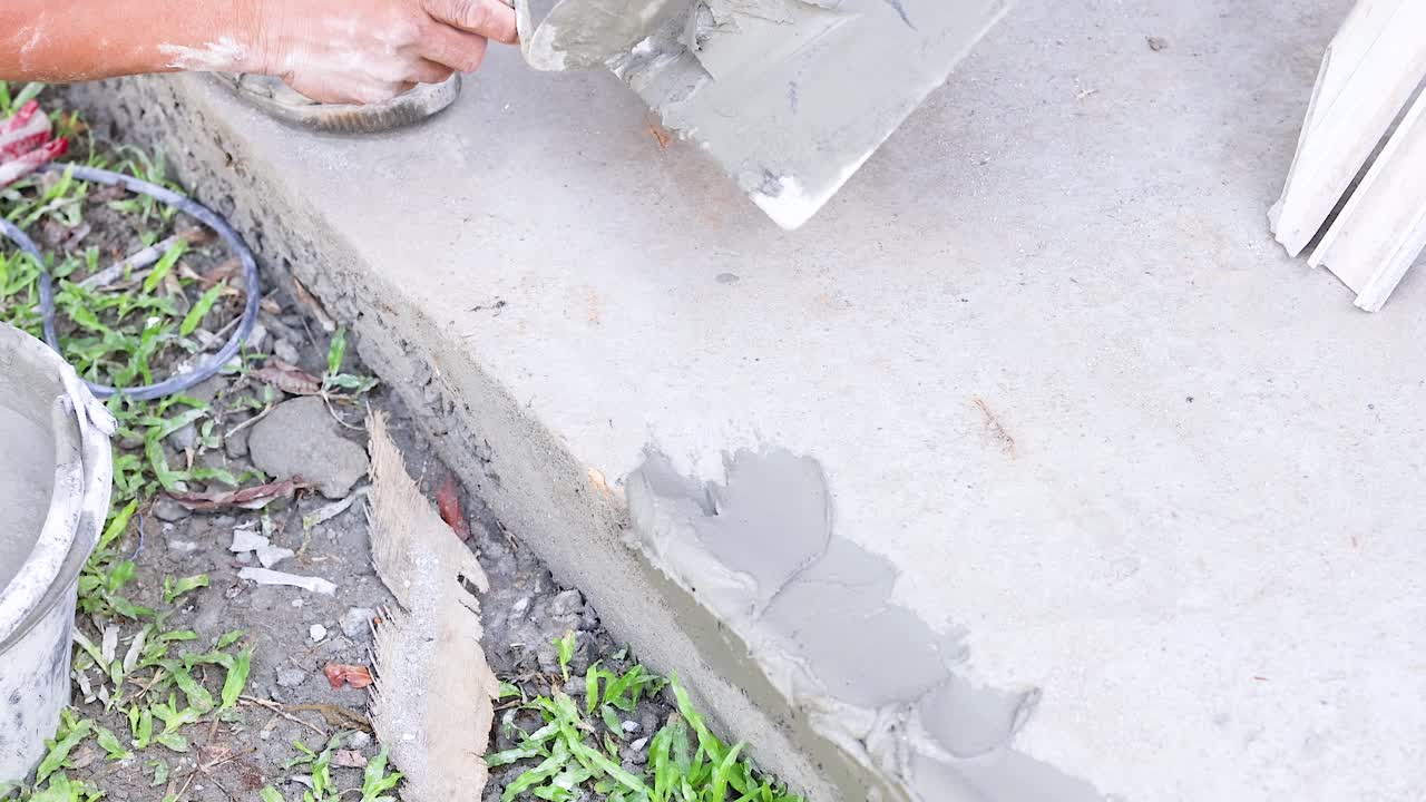 A worker applies cement to a concrete surface outdoors, showcasing repair techniques in natural lighting