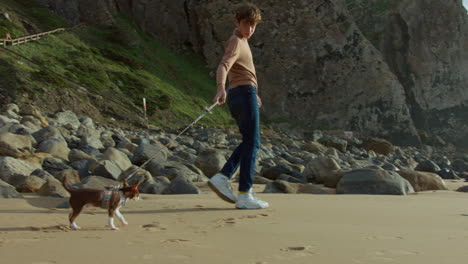 boy walking dog on rocky beach with cliffs