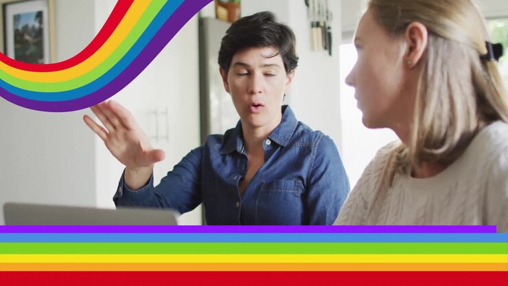 Animation of pride rainbow stripes over happy caucasian lesbian couple using laptop and talking