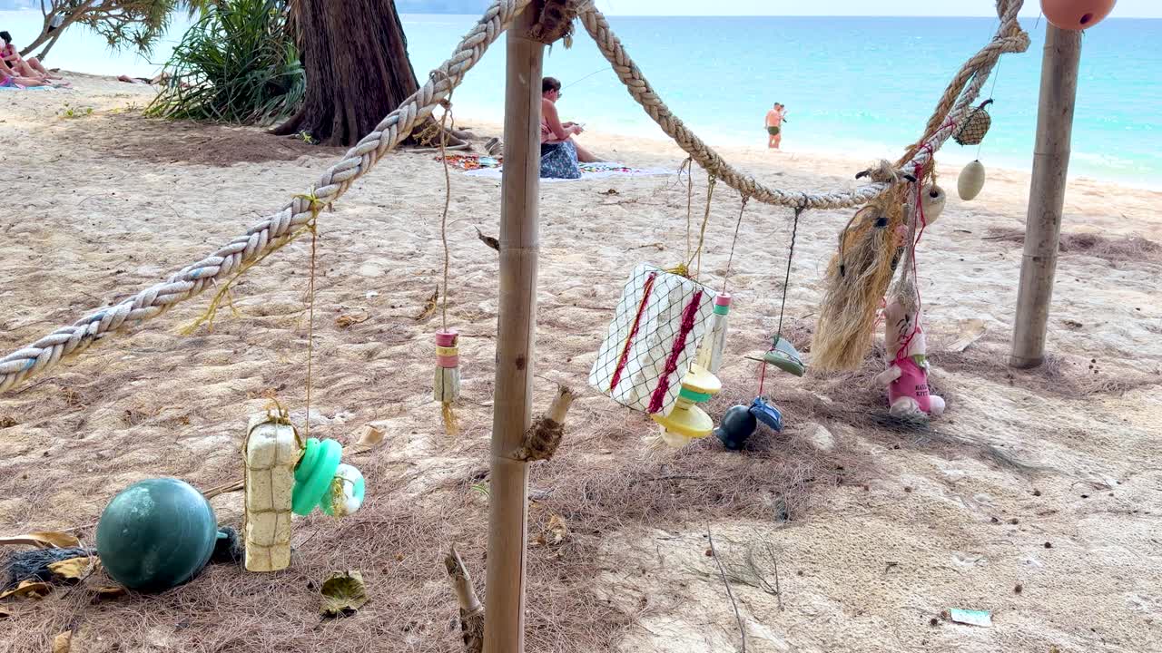 Ampia inquadratura statica di plastica oceanica raccolta e detriti da pesca appesi su una spiaggia tropicale.