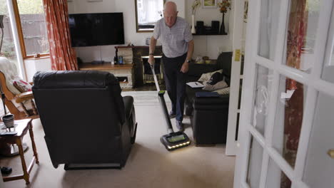 senior man vacuuming living room