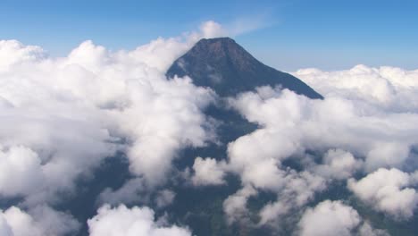 vista aérea del pico solitario del volcán agua que emerge por encima de una densa cubierta de nubes blancas bajo un cielo azul claro, mostrando la grandeza de la naturaleza