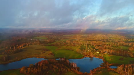 aerial drone shot of beautiful rural landscape with small lakes visible through white clouds during morning time