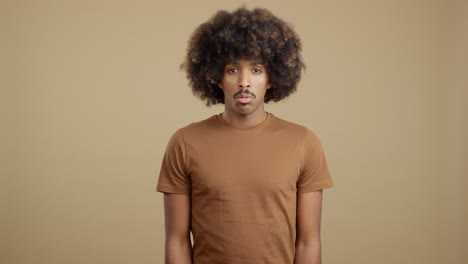 a man with an afro and mustache shows a serious expression, then looks down in shame or sadness.