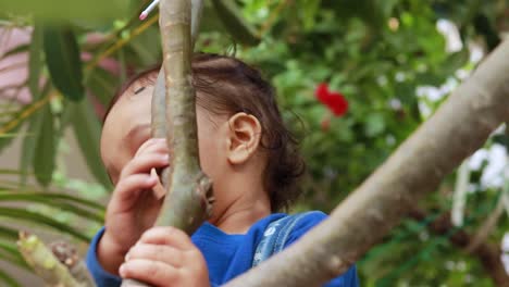 innocent infant holding tree branch with cute facial expression at day from flat angle