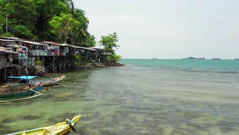 drone shot of wild indian ocean with shanty town on the thick forest shore side