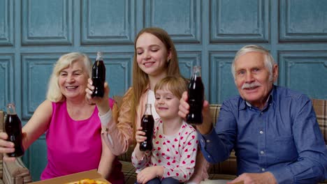 happy multigenerational family having lunch party at home, eating pizza food, raising toast together