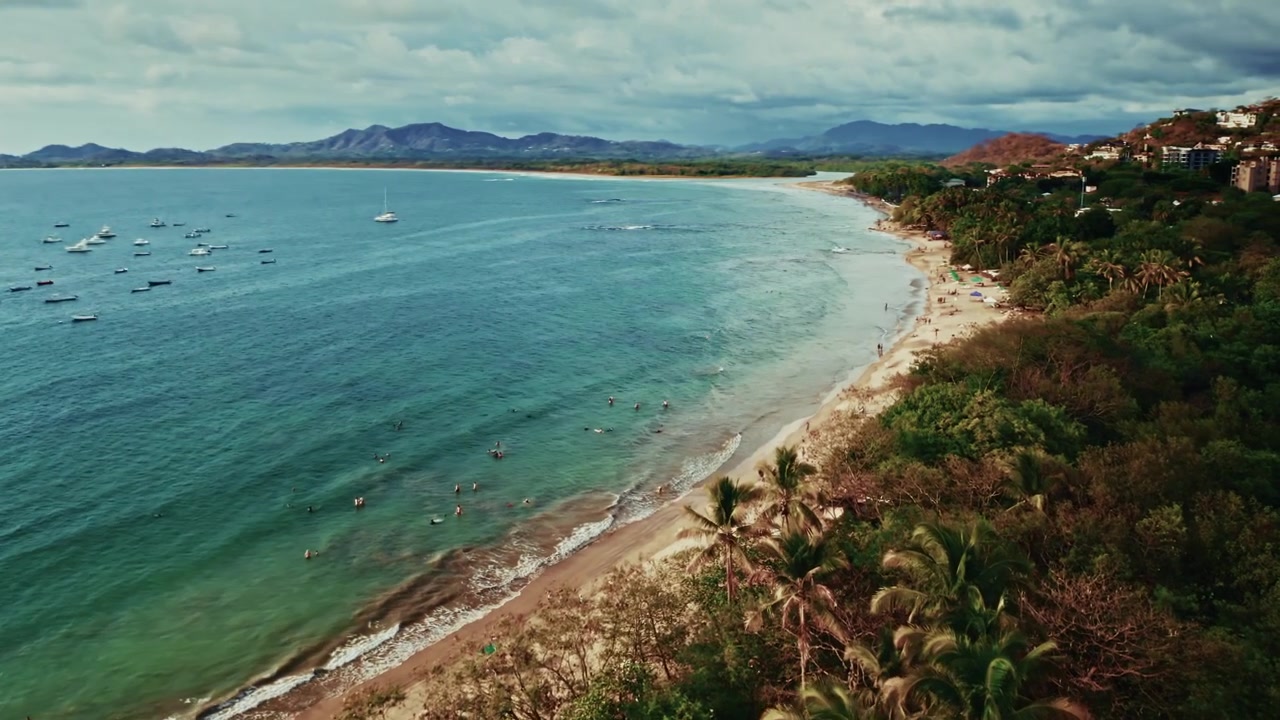 Ripresa aerea con drone sulla spiaggia tropicale di Tamarindo in Costa Rica. Vista dall'alto dell'Oceano Pacifico e della lunga spiaggia sabbiosa. Destinazione perfetta per gli appassionati di sport acquatici