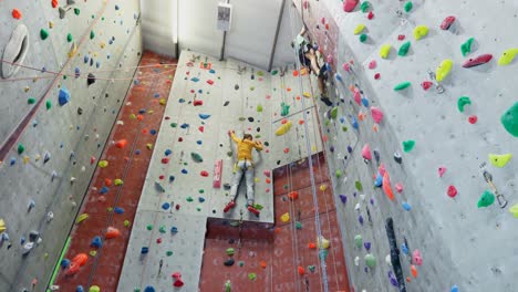 man and woman practicing rock climbing in fitness studio 4k