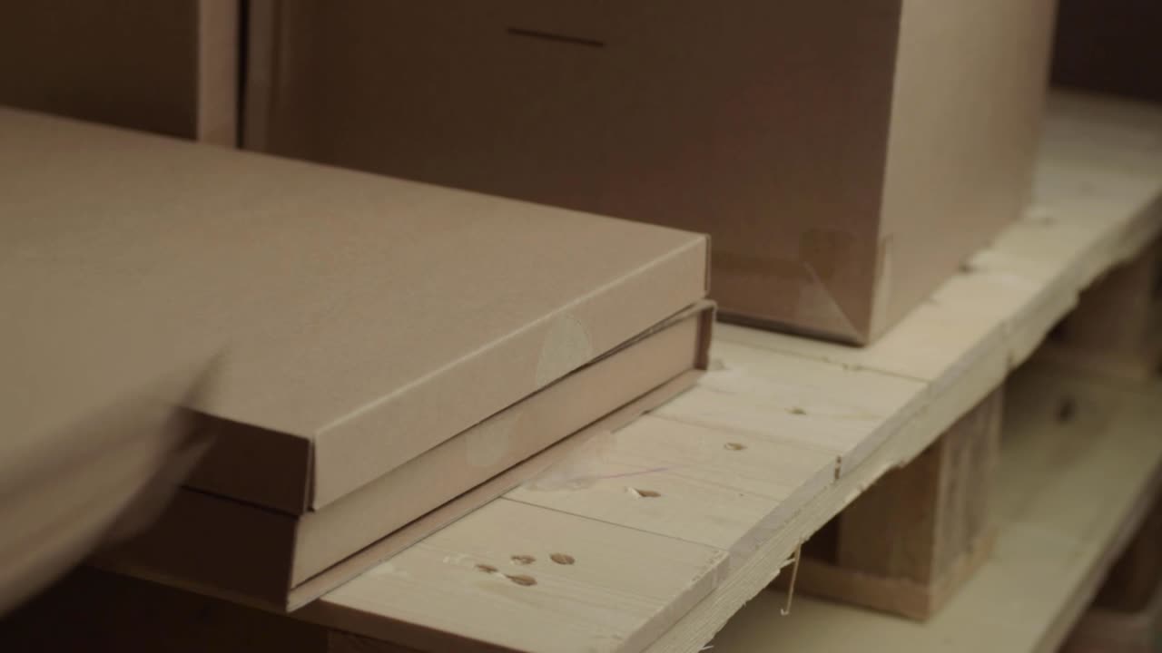 나무 팔레트에 있는 손으로 움직이는 판지 상자