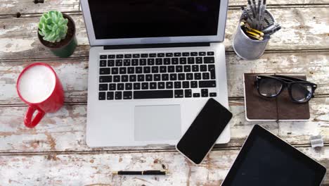 laptop, digital tablet, mobile phone and other belongings on wooden plank