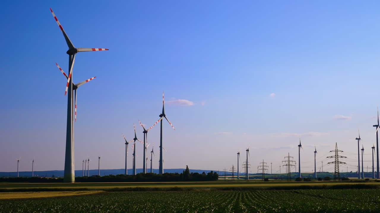 Wind turbines produce clean energy. Large wind turbines stand tall in green fields, showcasing renewable energy generation under a clear sky at sunset