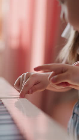 toddler boy presses digital piano keys following elder sister at home lesson closeup. friendly siblings learn music playing together on blurry background