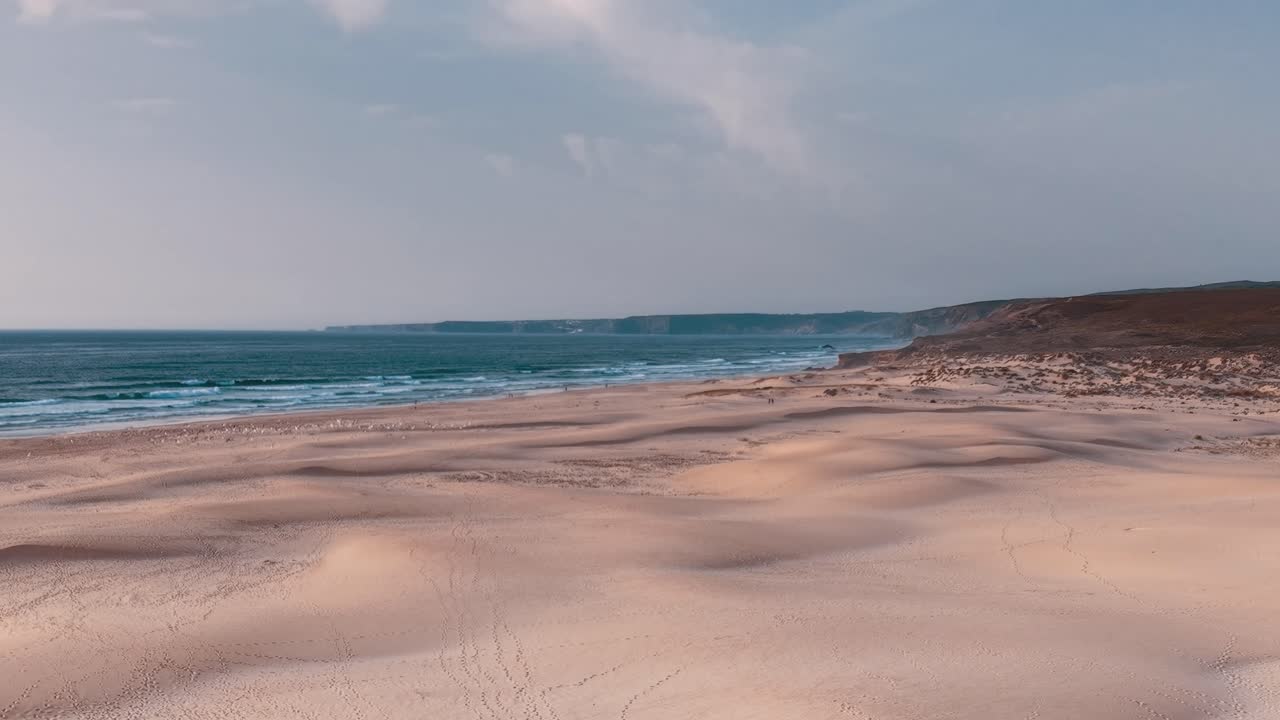 Kystlinjeudsigt over sandstrand i Portugal i den tidlige aftenbelysning