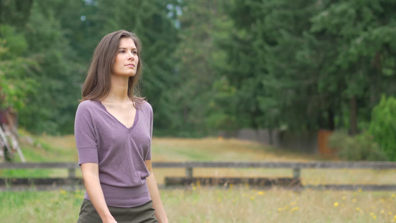 Gorgeous young woman walking in a rural field with no bra