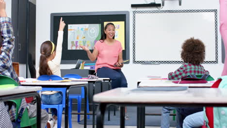 in school, teacher engaging with students raising hands in classroom discussion