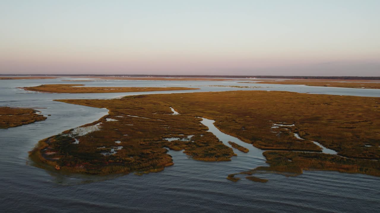 Marsh swamp land of barrier islands connect to open ocean at sunset, aerial dolly