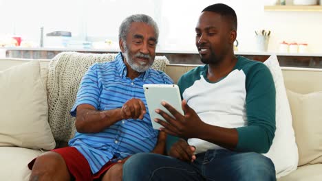 Father-and-son-using-digital-tablet-in-living-room