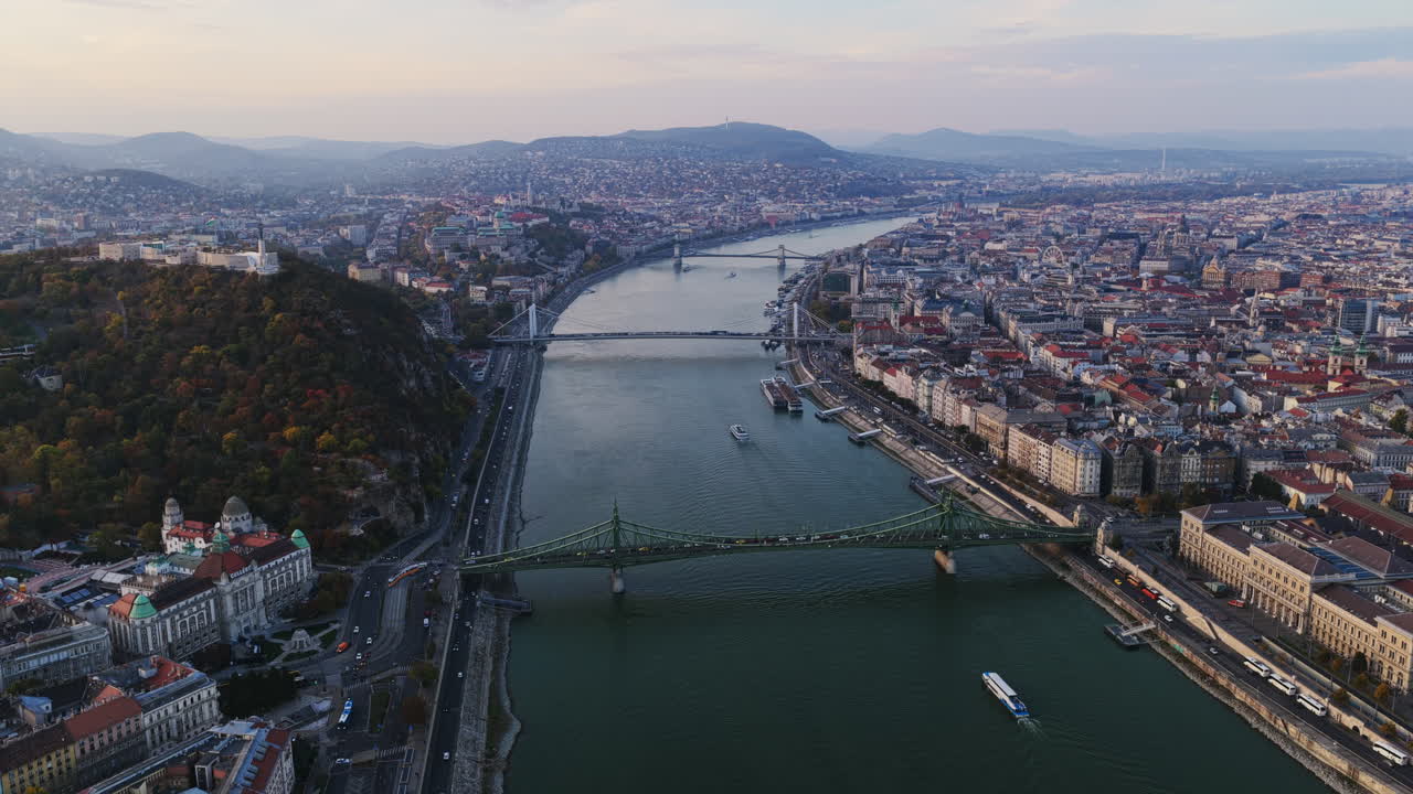 Il Ponte della Libertà brilla sul Danubio mentre tram e barche si muovono sotto, mostrando il vivace ritmo urbano di Budapest