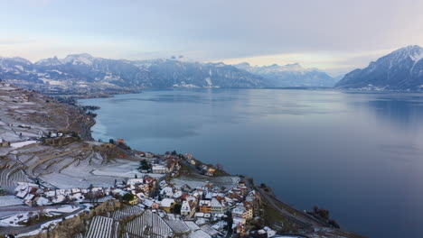 Volar-Por-El-Pueblo-De-Rivaz-En-Terrazas-De-Viñedos-De-Lavaux-Con-Alpes-Suizos-En-El-Fondo-Durante-El-Invierno-En-Vaud,-Suiza